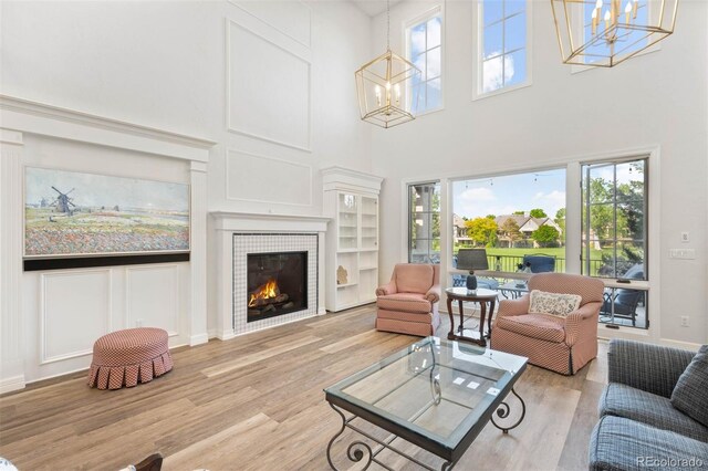 9151 E Harvard Ave, Denver, CO 80231 - living area featuring a chandelier, light wood-type flooring, plenty of natural light, a towering ceiling, and a fireplace