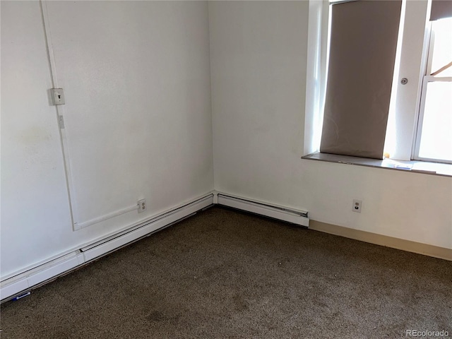 spare room featuring baseboards, a baseboard heating unit, and dark carpet