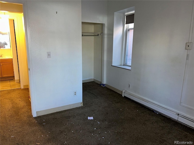 unfurnished bedroom featuring a baseboard radiator, a closet, and baseboards