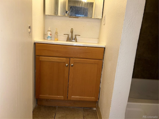 bathroom with a washtub, tile patterned flooring, and vanity