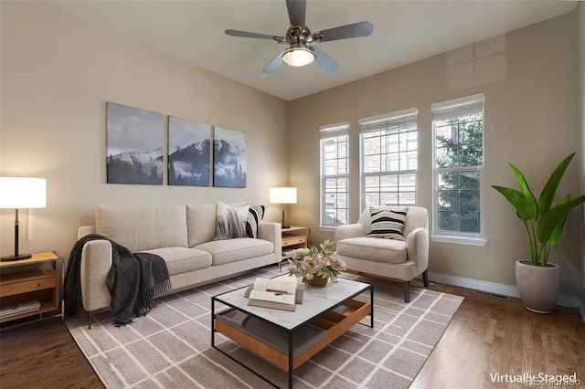 living room featuring visible vents, wood finished floors, baseboards, and ceiling fan