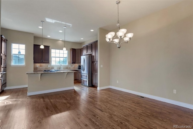 kitchen with a breakfast bar area, dark wood-style floors, visible vents, stainless steel appliances, and dark brown cabinetry