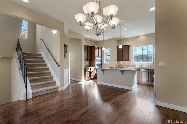 kitchen featuring a center island, baseboards, dark wood finished floors, a kitchen bar, and stainless steel appliances