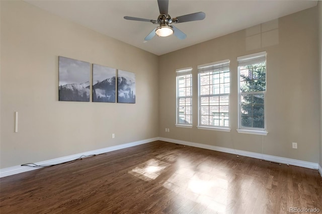 unfurnished room with dark wood-style floors, ceiling fan, and baseboards