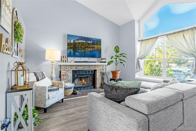 living room featuring a brick fireplace, wood finished floors, and vaulted ceiling