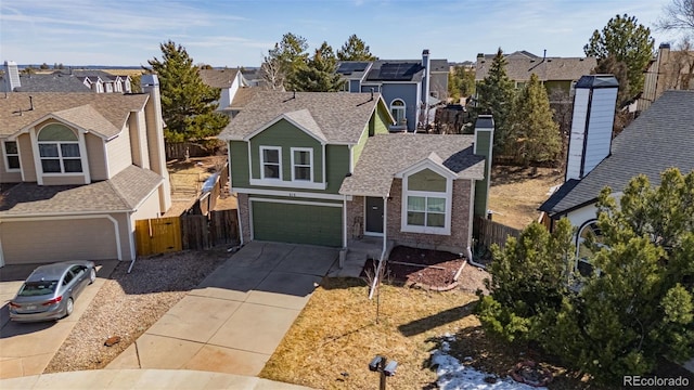 traditional home with fence, a residential view, concrete driveway, an attached garage, and a shingled roof