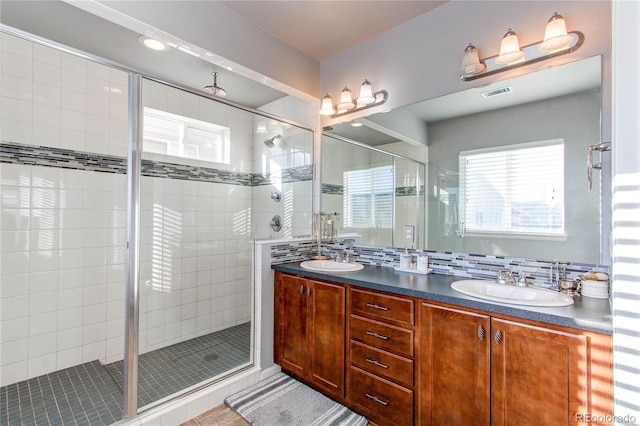 bathroom with vanity, decorative backsplash, a shower with shower door, and tile patterned floors