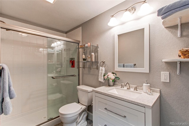 bathroom with a shower with door, vanity, and toilet