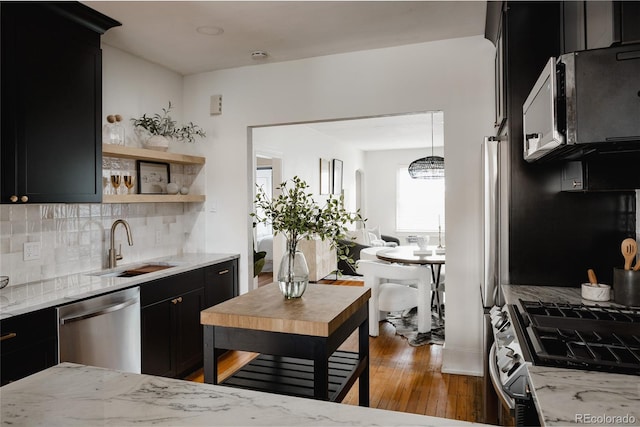 kitchen with backsplash, sink, dark hardwood / wood-style floors, light stone countertops, and stainless steel appliances