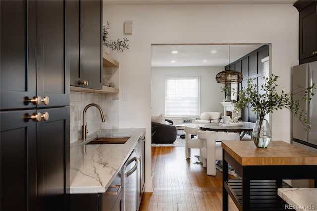 kitchen featuring backsplash, sink, light stone countertops, appliances with stainless steel finishes, and dark hardwood / wood-style flooring