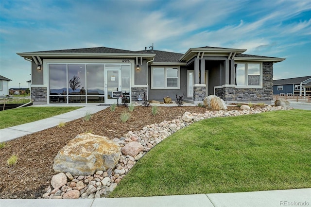 prairie-style home featuring stone siding, a front lawn, and stucco siding