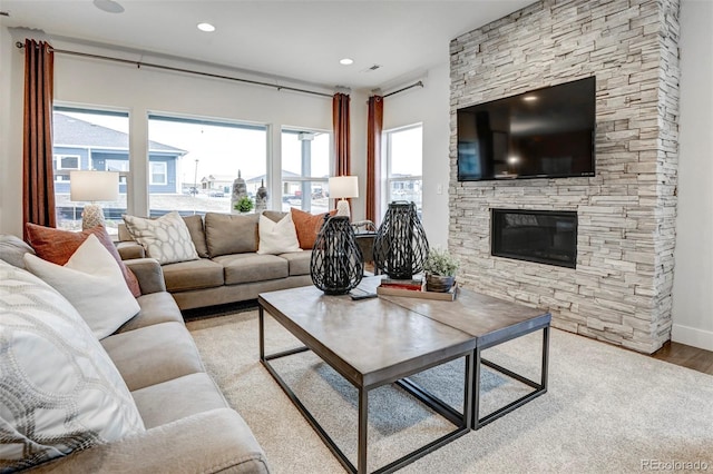 living room featuring baseboards, a stone fireplace, wood finished floors, and recessed lighting