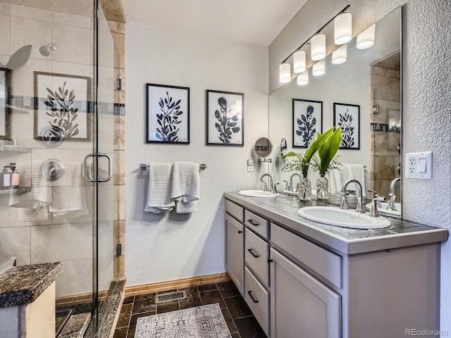 32663 Donna Dr, Conifer, CO 80433 - bathroom with double vanity, a textured wall, a shower stall, and stone tile floors