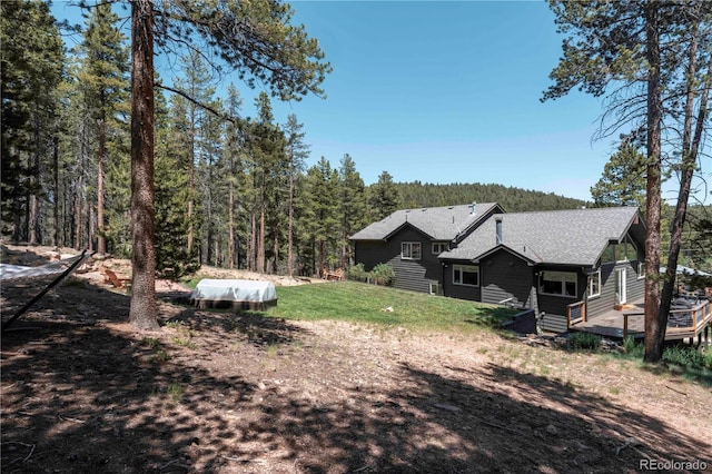 32663 Donna Dr, Conifer, CO 80433 - back of property with a wooden deck, a forest view, a shingled roof, and a yard