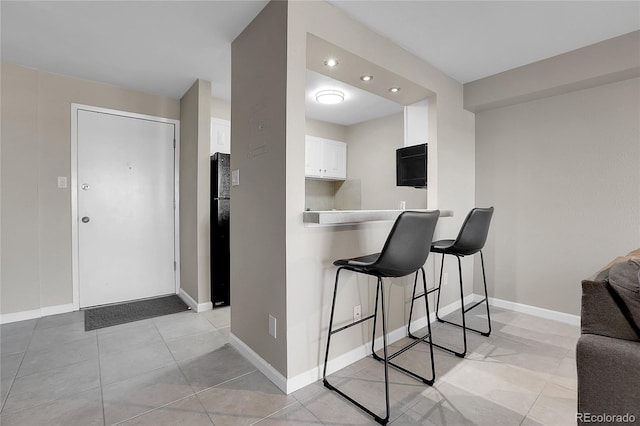 kitchen featuring white cabinets, a kitchen bar, and kitchen peninsula