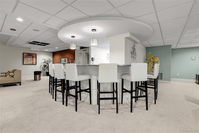 carpeted dining room featuring a drop ceiling