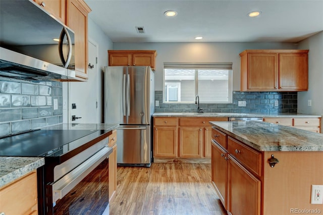 3769 Dahlia St, Denver, CO 80207 - kitchen featuring appliances with stainless steel finishes, a sink, backsplash, light wood-style flooring, and recessed lighting