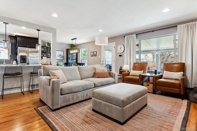 living area with light wood-style flooring, plenty of natural light, and recessed lighting