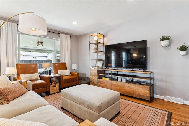 living area featuring visible vents, baseboards, recessed lighting, and wood finished floors