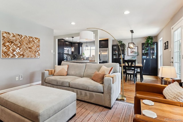 living area with light wood-style floors, baseboards, and recessed lighting