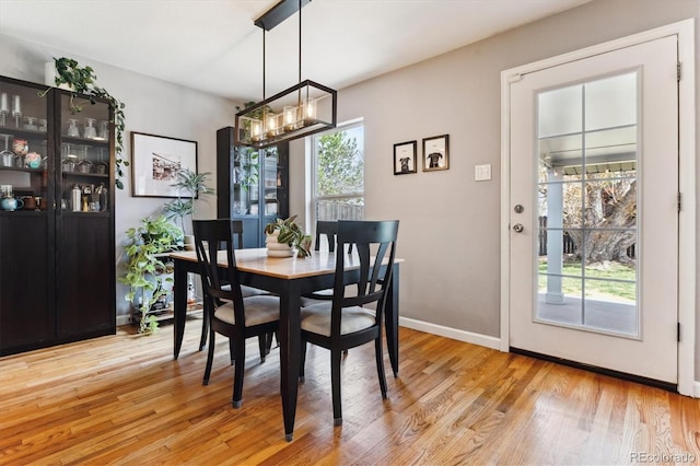 dining room with a chandelier, a healthy amount of sunlight, light wood finished floors, and baseboards