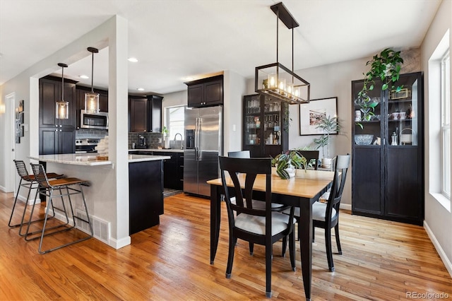 dining space featuring recessed lighting, light wood-style flooring, baseboards, and an inviting chandelier