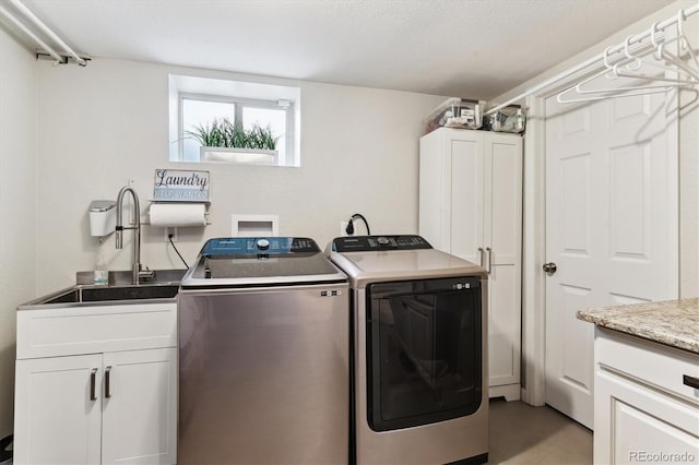 washroom featuring washing machine and clothes dryer, a sink, and cabinet space