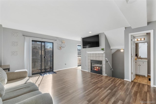 living room with a tile fireplace, a healthy amount of sunlight, hardwood / wood-style flooring, and sink