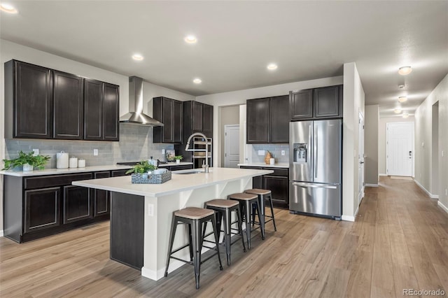 1677 Meagan Way, Erie, CO 80516 - kitchen with stainless steel fridge, wall chimney exhaust hood, a sink, a breakfast bar, and tasteful backsplash