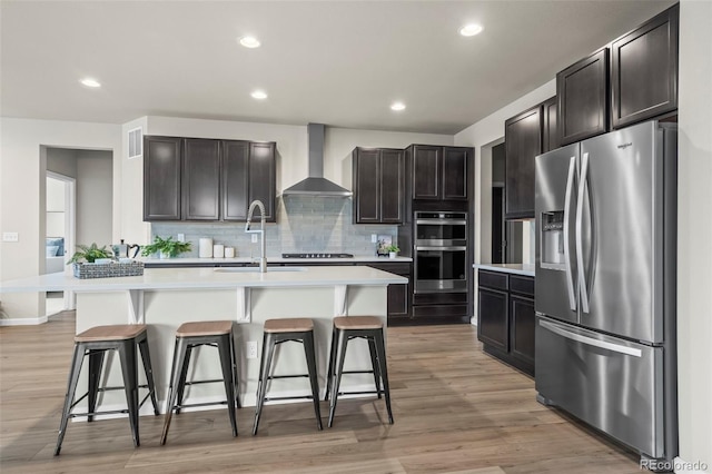1677 Meagan Way, Erie, CO 80516 - kitchen with appliances with stainless steel finishes, wall chimney exhaust hood, a sink, a breakfast bar, and recessed lighting