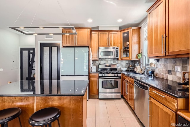 1950 N Logan St Unit 108, Denver, CO 80203 - kitchen with appliances with stainless steel finishes, brown cabinetry, tasteful backsplash, and recessed lighting