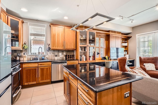 1950 N Logan St Unit 108, Denver, CO 80203 - kitchen featuring stainless steel appliances, a sink, open floor plan, tasteful backsplash, and glass insert cabinets