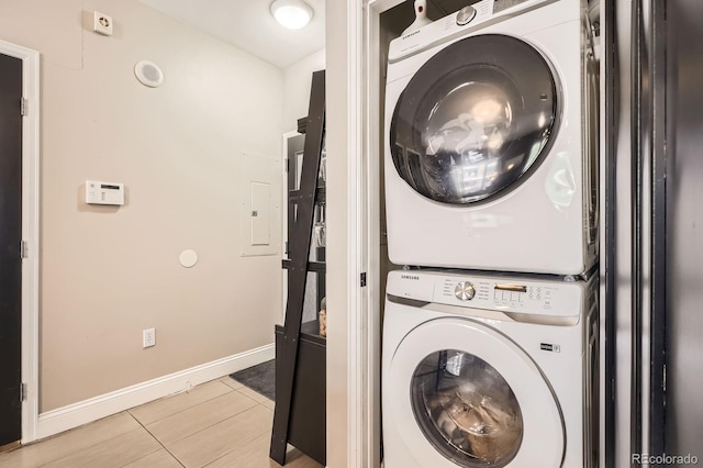 1950 N Logan St Unit 108, Denver, CO 80203 - washroom featuring stacked washer and clothes dryer, light tile patterned flooring, baseboards, and electric panel