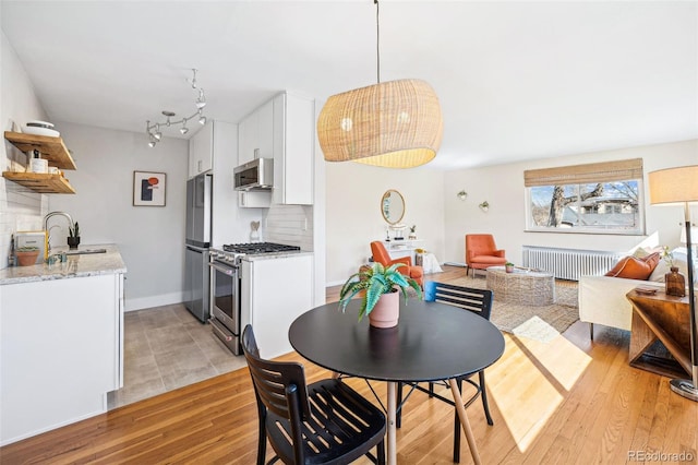 dining area featuring light wood-style flooring, radiator heating unit, and baseboards