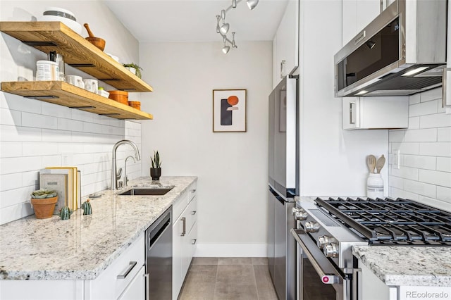 kitchen with a sink, tasteful backsplash, appliances with stainless steel finishes, white cabinets, and baseboards