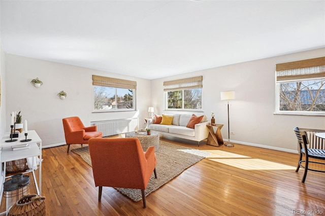 living area featuring baseboards, wood-type flooring, and radiator heating unit