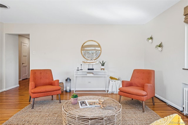 living area featuring visible vents, baseboards, and wood finished floors