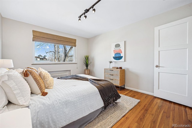 bedroom featuring track lighting, baseboards, and wood finished floors