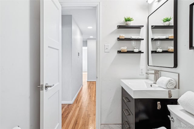 bathroom with baseboards, toilet, wood finished floors, and vanity