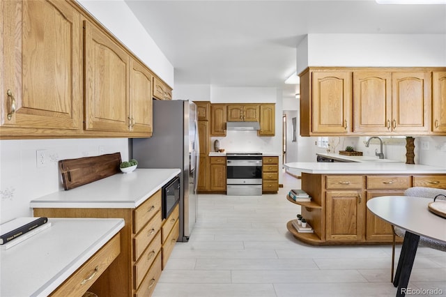 kitchen with appliances with stainless steel finishes, a sink, light countertops, and decorative backsplash