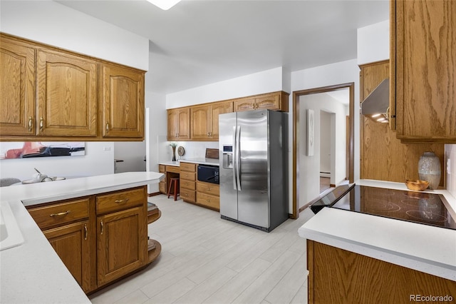 kitchen featuring stainless steel fridge with ice dispenser, under cabinet range hood, light countertops, brown cabinetry, and light wood-type flooring