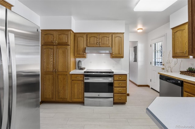 kitchen with appliances with stainless steel finishes, under cabinet range hood, light countertops, and brown cabinetry