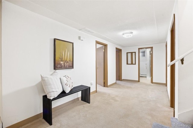 corridor featuring light colored carpet, a baseboard heating unit, and baseboards