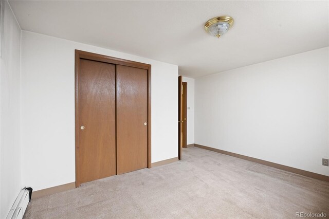 unfurnished bedroom with a baseboard radiator, light colored carpet, and a closet