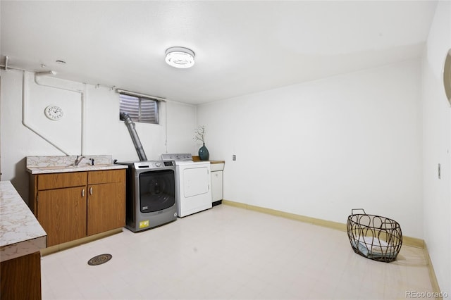 clothes washing area featuring independent washer and dryer, light flooring, baseboards, and cabinet space