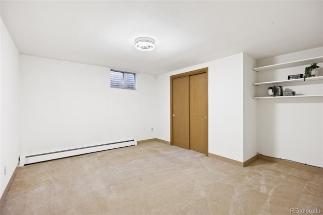unfurnished bedroom with baseboard heating, light colored carpet, a closet, and baseboards