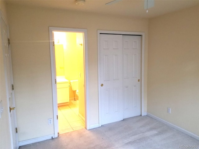 unfurnished bedroom with light carpet, ensuite bathroom, a closet, and ceiling fan