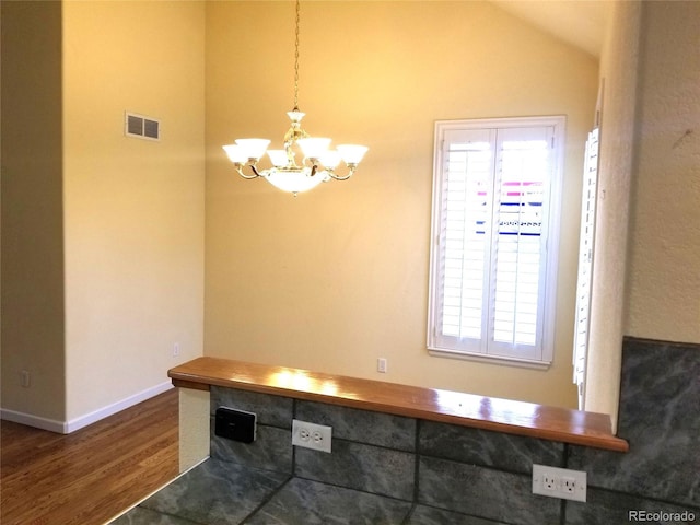 unfurnished dining area featuring vaulted ceiling, an inviting chandelier, and dark wood-type flooring