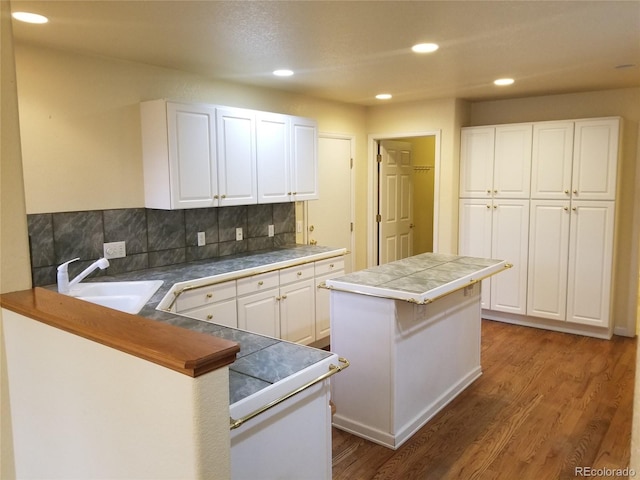 kitchen with tile counters, sink, dark hardwood / wood-style floors, kitchen peninsula, and white cabinets