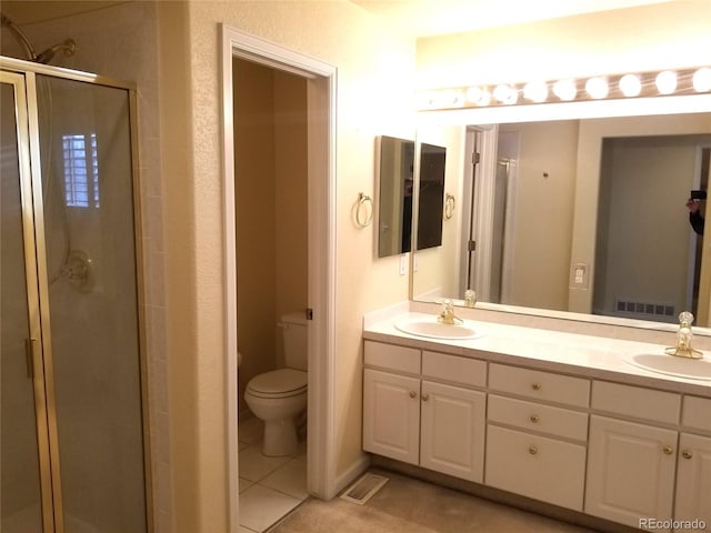 bathroom featuring tile patterned flooring, vanity, toilet, and walk in shower